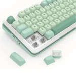 Pastel mint-green mechanical keyboard with several keycaps removed, exposing the mechanical switches underneath.