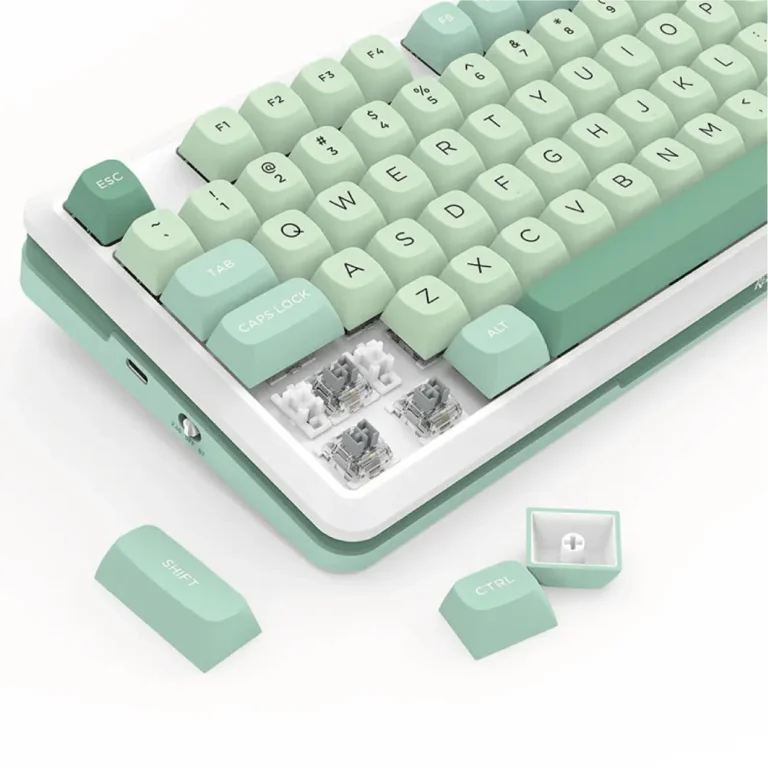 Pastel mint-green mechanical keyboard with several keycaps removed, exposing the mechanical switches underneath.
