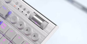 Close-up of a metallic keyboard with a textured roller control and pink backlit keys.